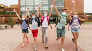 Kids in face masks raising hands 